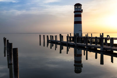 Pier on sea against sky during sunset