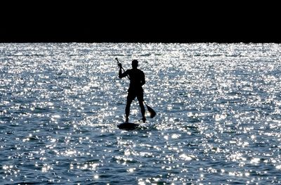 Silhouette of man standing in sea against sky