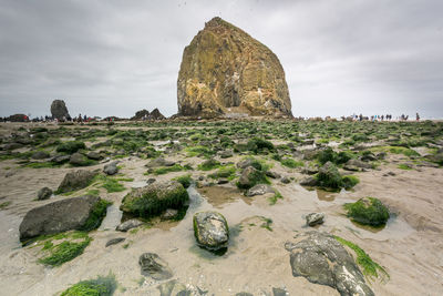 View of rock formations on coast against cloudy sky