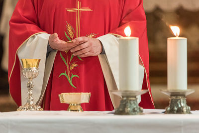 Midsection of priest praying at table in church