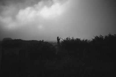 Silhouette man standing on field against sky