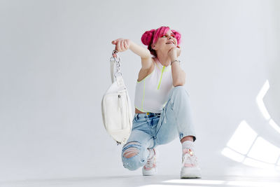 Full length of young woman with arms raised against white background