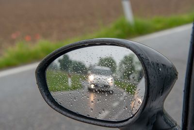 Close-up of raindrops on side-view mirror