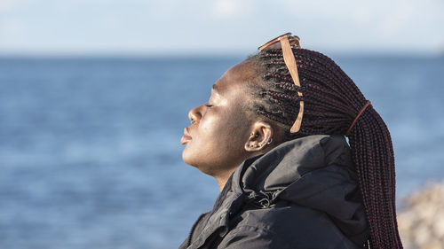 African woman sits by the swedish baltic sea and enjoys the sunset