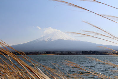 Scenic view of lake by snowcapped mountains against sky