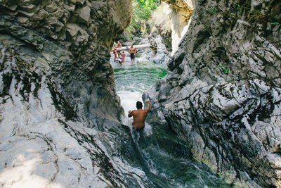 High angle view of man standing on rock by river