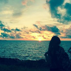 Rear view of woman photographing sea at sunset