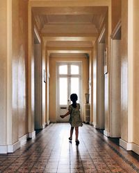 Rear view of woman walking in corridor of building