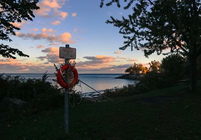 Bicycle sign by sea against sky during sunset