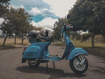 Side view of motor scooter on road against sky