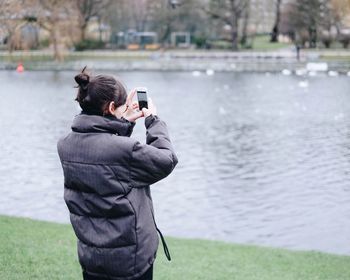 Rear view of woman photographing in river