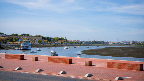 Boats in harbor by buildings against sky