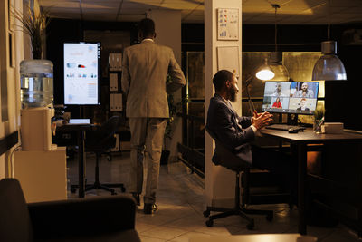 Rear view of man using laptop on table