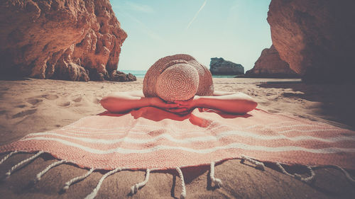 Rear view of woman sitting on sand at beach