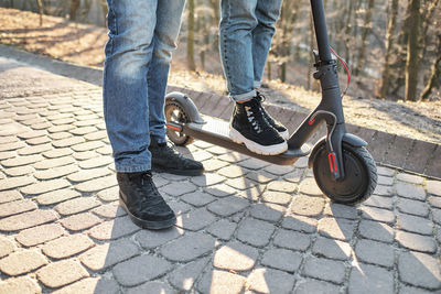 Loving young millennials having fun walking on an electric scooter