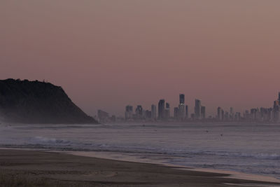 Hazy pink sunset from bush fire smoke at the gold coast with city high rises in the background.