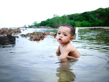 Portrait of shirtless boy swimming in lake