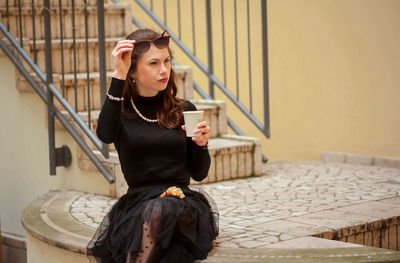 Young woman looking at camera while sitting on mobile phone