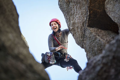 Low angle view of happy woman rock climbing