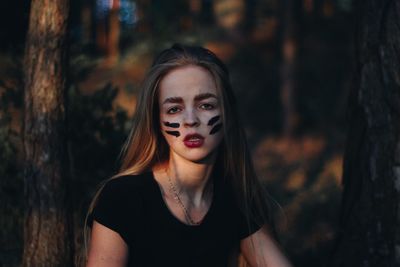 Portrait of woman with face paint in forest