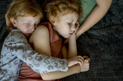 Affectionate siblings hugging each other and sleeping on mother's lap