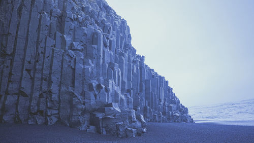 Rock formations on snow covered mountain against sky