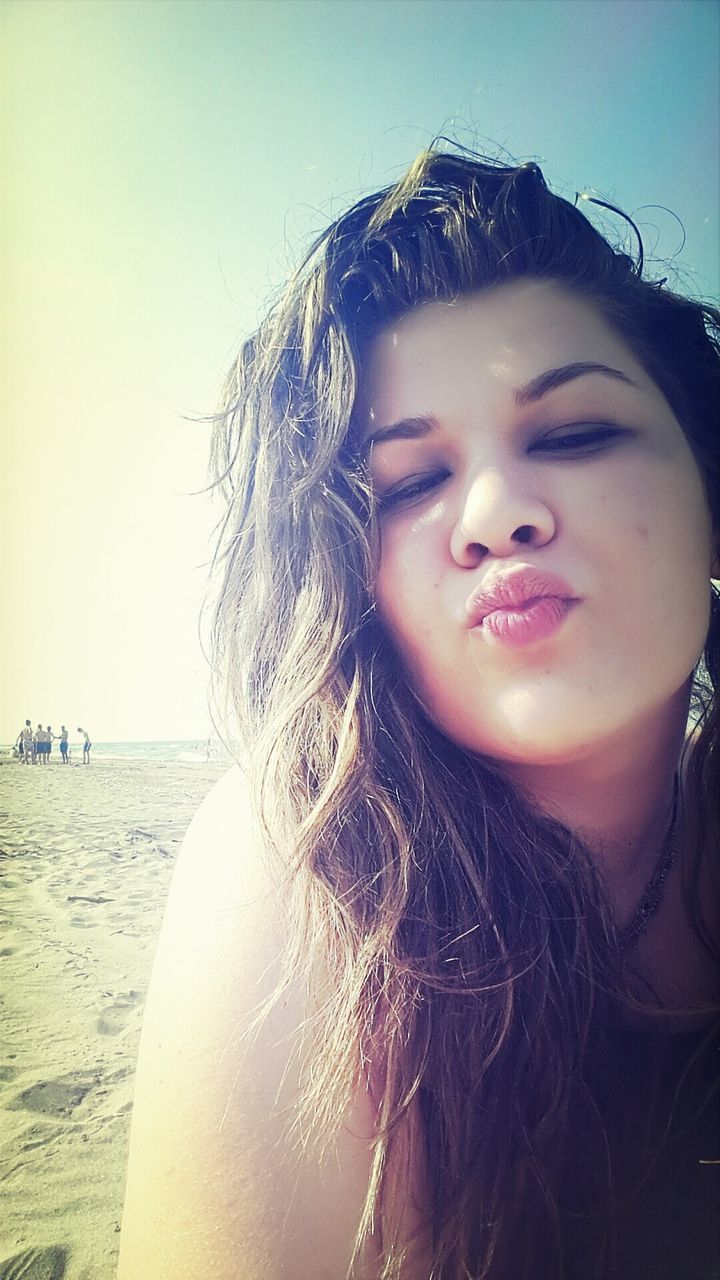 water, young adult, young women, person, long hair, lifestyles, leisure activity, sea, portrait, looking at camera, headshot, beach, front view, sky, clear sky, sunlight, outdoors