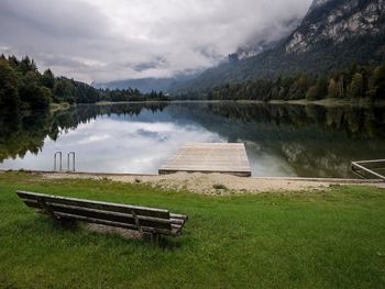 View of bench at lakeshore against sky