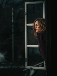 Woman looking through window at night