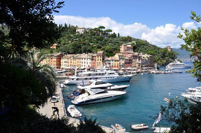 Sailboats moored in sea by townscape against sky portofino 