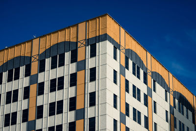 Low angle view of office building against blue sky