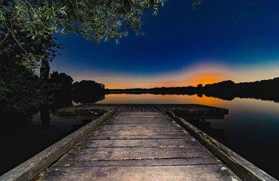 Pier over lake against sky at night