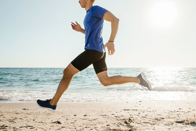 Man running on beach against clear sky