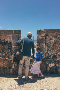 Rear view of man and woman walking on wall