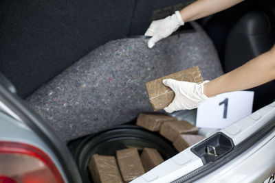 Cropped image of investigator searching for smuggled drug in car trunk