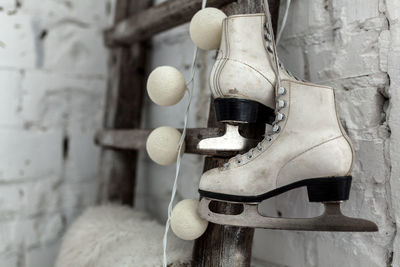 Close-up of ice skates hanging on ladder against wall