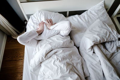 High angle view of man covering face with pillow