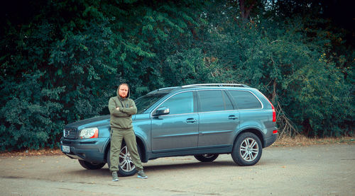 Portrait of man standing on road against trees