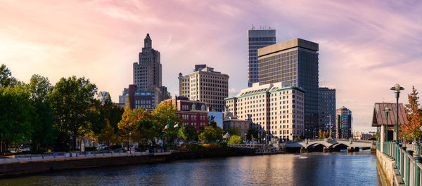 Modern buildings by river against sky in city