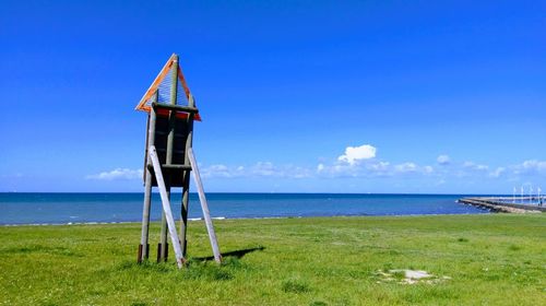 Lifeguard hut on beach against blue sky