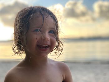 Portrait of happy boy at beach against sky