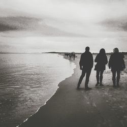 Rear view of people walking on beach