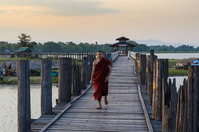 Rear view of woman on pier against sky