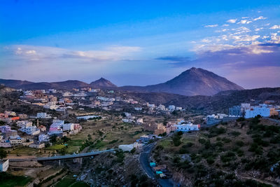 High angle view of townscape and mountains against blue sky