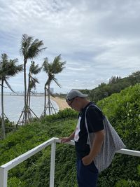 Man standing by railing against sky