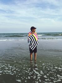 Man standing at beach against cloudy sky