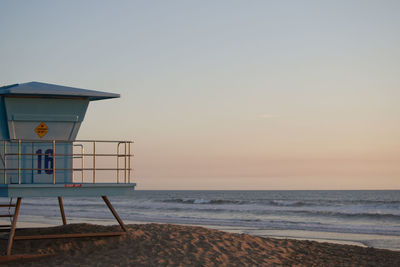 Hut on beach against sky during sunset