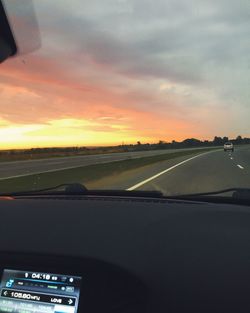 Road seen through car windshield during sunset