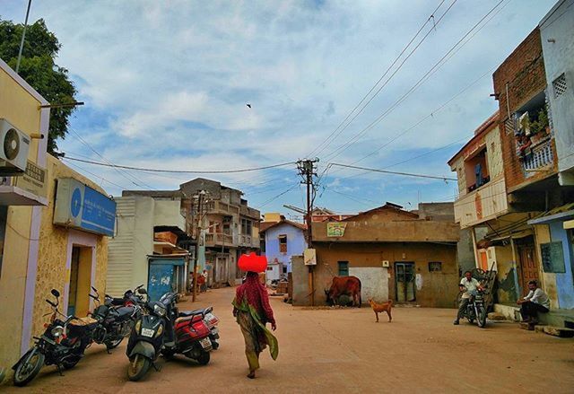 building exterior, architecture, built structure, sky, residential structure, street, residential building, men, transportation, house, bicycle, city, power line, land vehicle, mode of transport, walking, cloud - sky, building, cloud