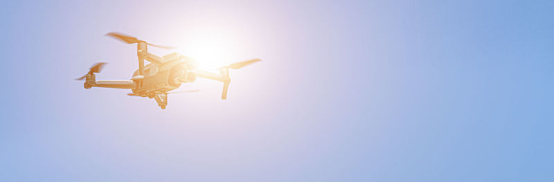 Low angle view of drone flying against clear blue sky